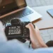 Developing A Photography Portfolio For College Applications 17 Person holding a DSLR camera showing manual settings screen at a desk