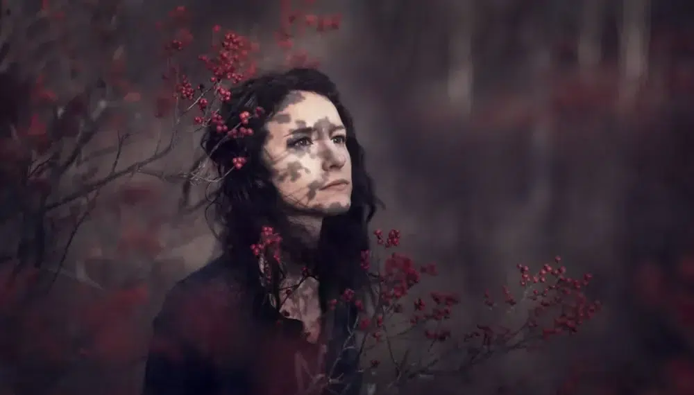 10 Portrait Photography Tips & Tricks Every Beginner Should Know 8 Moody portrait of a woman surrounded by red berries with dappled shadow on her face