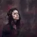 Moody portrait of a woman surrounded by red berries with dappled shadow on her face