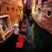 Gondolier steering through a narrow Venice canal lined with brick buildings
