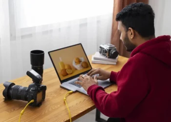 Photographer editing a food photo on a laptop with cameras and lenses nearby