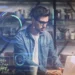 Man with glasses working on a laptop surrounded by glowing AI data visuals