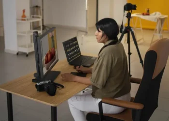Photographer editing images at a desk with a monitor, laptop, and camera nearby