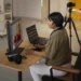 Photographer editing images at a desk with a monitor, laptop, and camera nearby