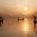 Fishermen casting nets from boats at golden sunrise, countryside life