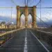 Symmetrical view of Brooklyn Bridge walkway with NYC skyline in background