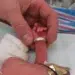 Newborn's tiny hand gripping father's wedding ring finger - storytelling photography