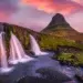 Waterfalls cascading before a iconic peaked mountain under a vivid pink sunset sky