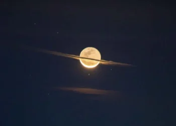 A full moon glowing through thin clouds in a dark night sky