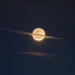 A full moon glowing through thin clouds in a dark night sky