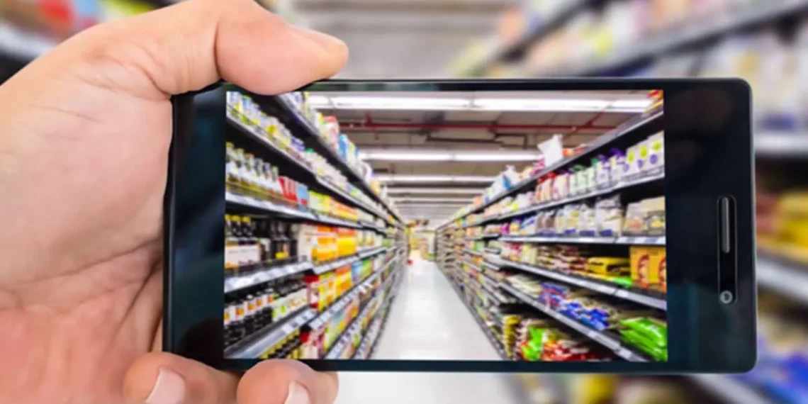 Hand holding a smartphone photographing a supermarket aisle with shelves