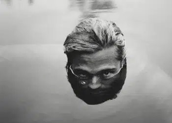 Man's face half-submerged in water, black and white film photography