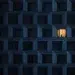 A solitary figure stands in the only lit window of a dark apartment building facade at night