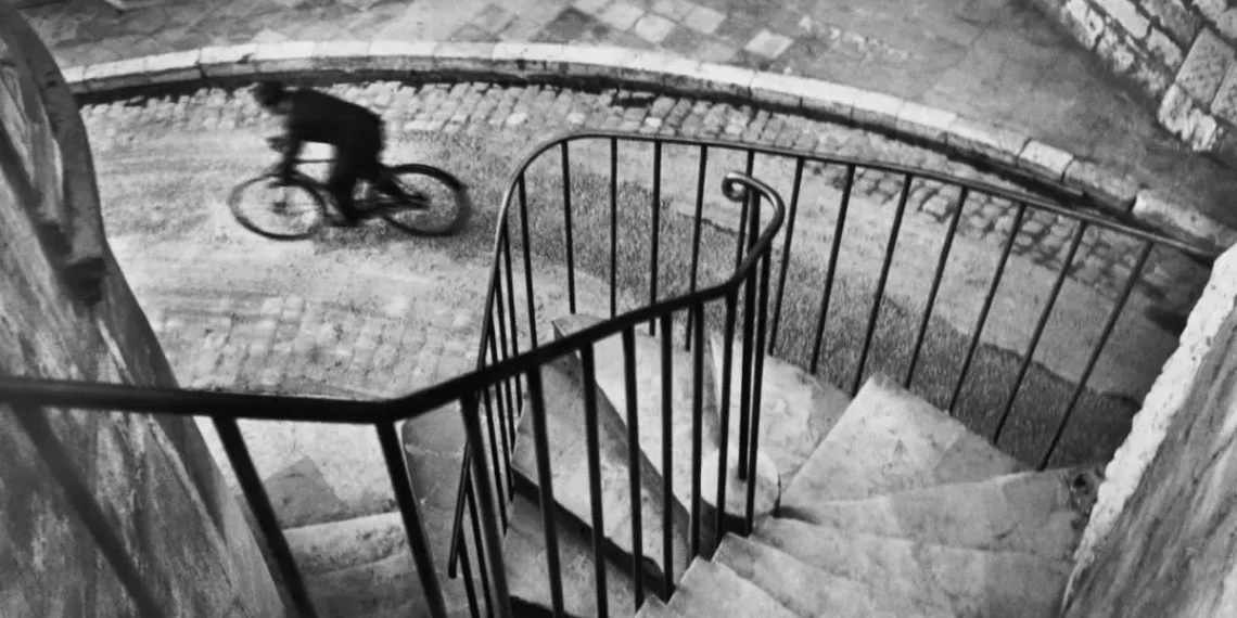 A blurred cyclist on cobblestones seen from above a spiral staircase