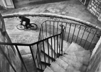 A blurred cyclist on cobblestones seen from above a spiral staircase