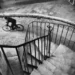 A blurred cyclist on cobblestones seen from above a spiral staircase
