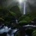 Tall waterfall with mossy rocks and misty forest stream, landscape photos around the world
