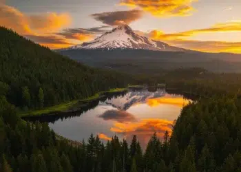 Snow-capped Mount Hood reflected in a forest lake under a fiery sunset - breathtaking landscape photography
