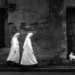 Two nuns walking past weathered wall with white rabbit, black and white daily life photo
