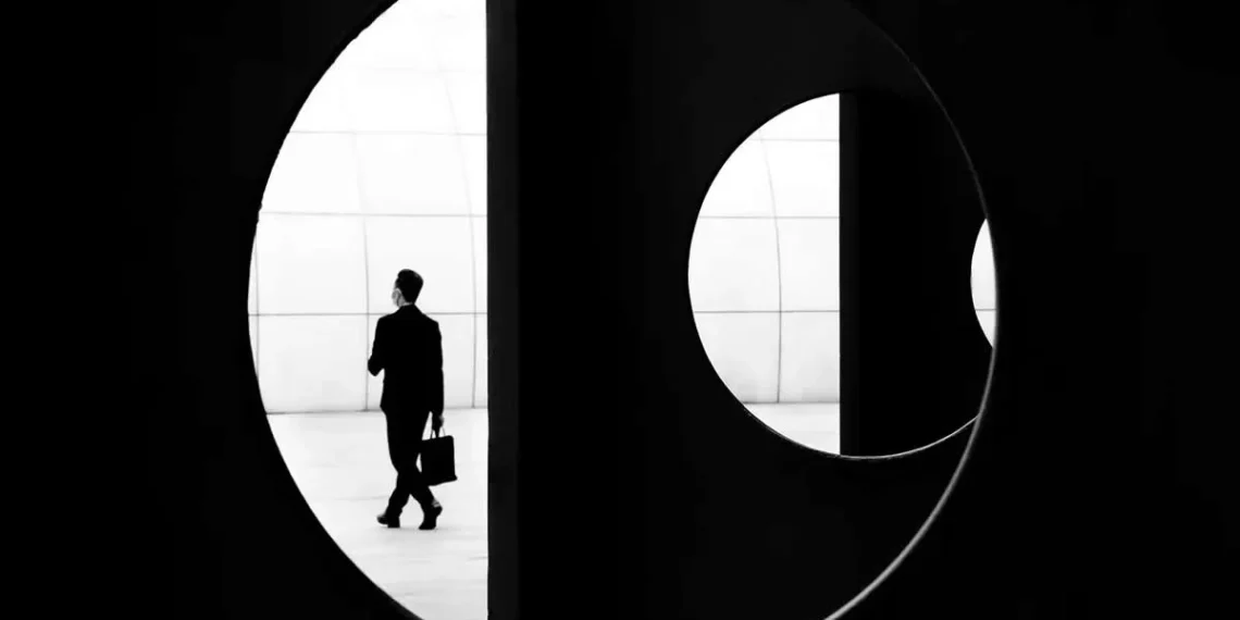 Suited figure framed through circular architectural opening