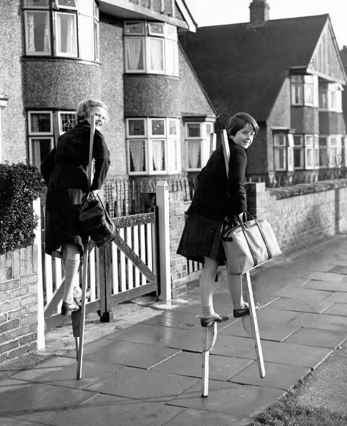 Two girls shopping for their mothers on stilts in Sidcup, England. Stilt-walking was a popular pastime for children in the 1950s