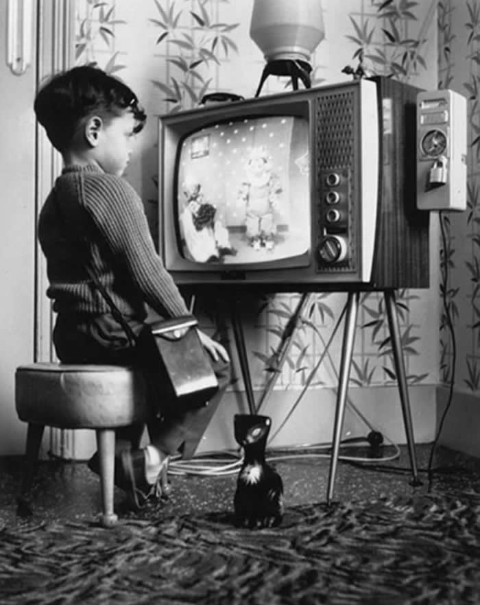 A youngster watching at home on a pay television in 1963. A slot meter on the right allows him to insert a sixpence coin for an hour of viewing.