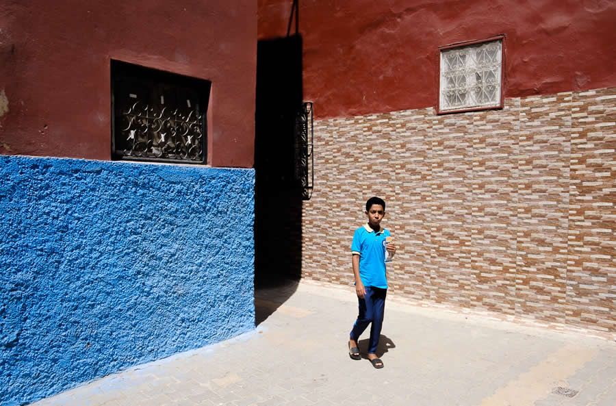 Streets of Morocco Boy walking in lanes with vibrant walls shadow and colors  - Captivating Street Photography by Giancarlo Zuccarone