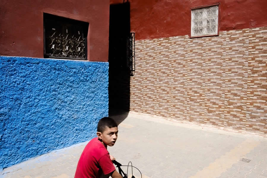 Streets of Morocco Boy walking in lanes with vibrant walls shadow and colors - Captivating Street Photography by Giancarlo Zuccarone