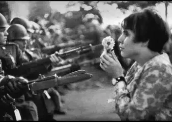 Young woman holding a flower facing armed soldiers