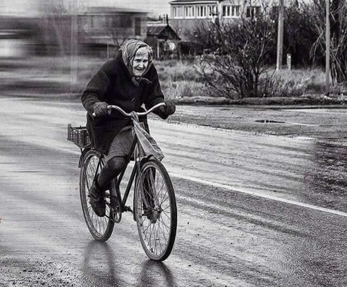 Elderly woman riding a bicycle through the city streets - Black and White Bicycle Photos of Everyday Life
