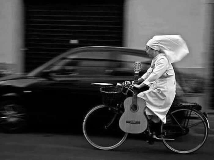 Nun riding a bicycle quickly down the road - Black and White Bicycle Photos of Everyday Life