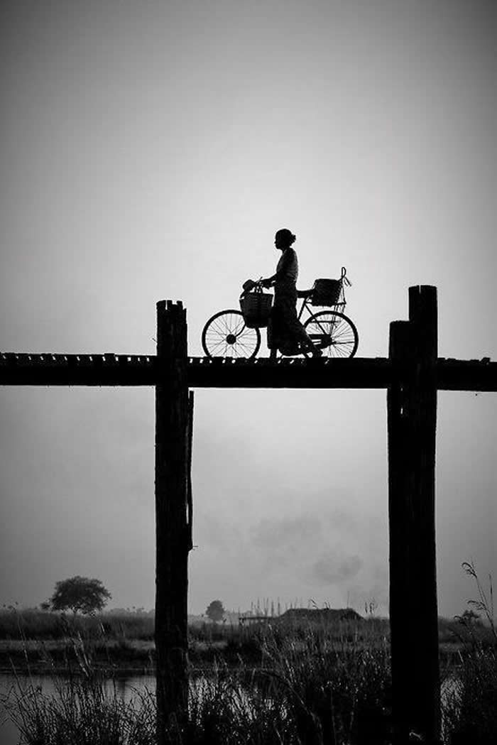 Woman walking her bicycle across a bridge - Black and White Bicycle Photos of Everyday Life