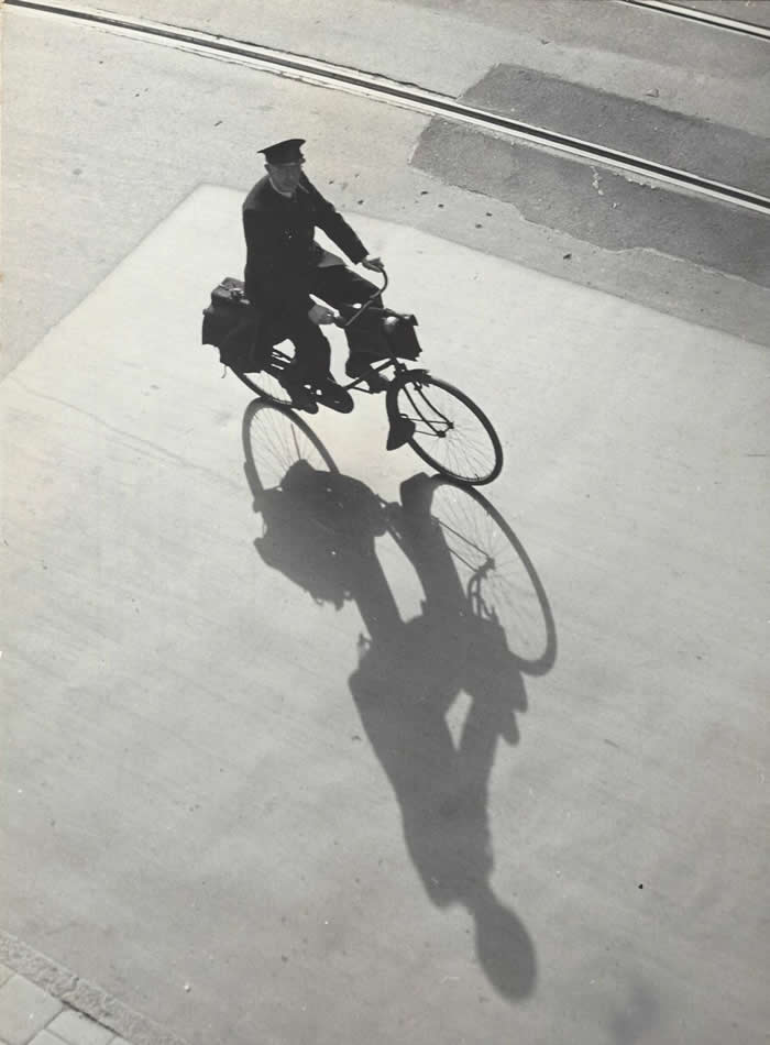 Postman cycling in backlight, Amsterdam, 1957 - Black and White Bicycle Photos of Everyday Life