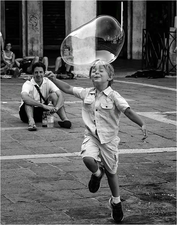 Boy playing with a giant water bubble - Pure Joy of Childhood Black and White Photos