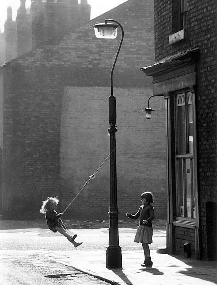Two girls playing on a street lamp pole - Pure Joy of Childhood Black and White Photos
