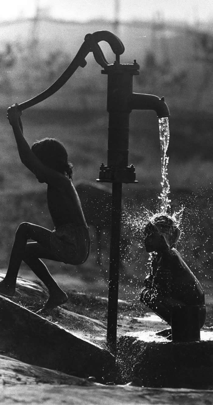 Kids taking a bath at a water pump - Pure Joy of Childhood Black and White Photos