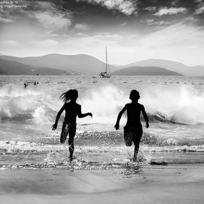 Brother and sister playing on the beach - Pure Joy of Childhood Black and White Photos