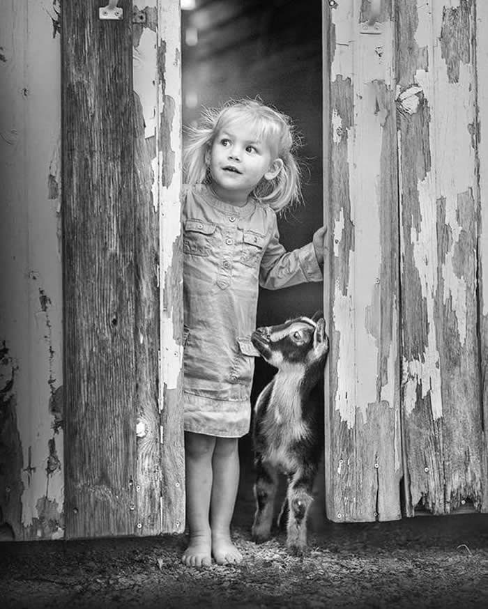 Kid with a goat near the doorway - Pure Joy of Childhood Black and White Photos