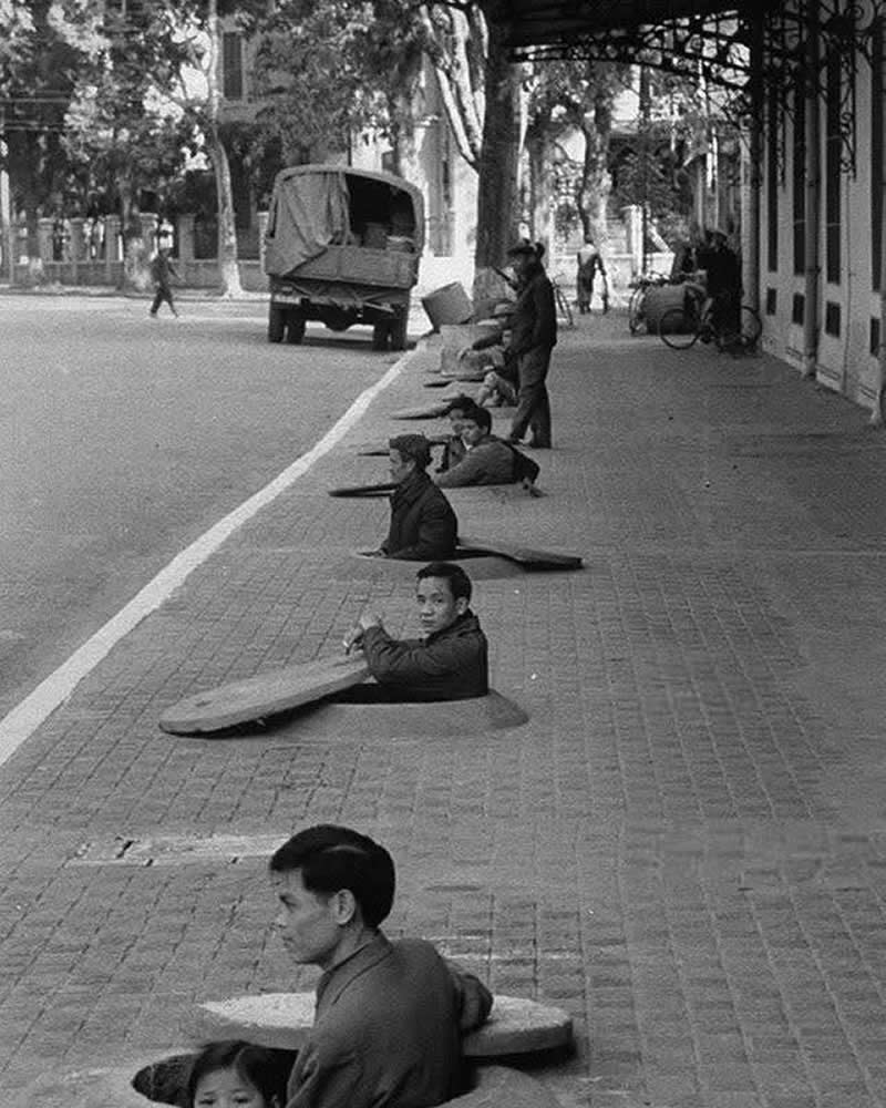 25 Powerful Historical Photos That Bring Forgotten Stories Back to Life 45 Hanoi residents shelter chest-deep in sidewalk bunkers as they await the all-clear during an air-raid warning. Hanoi, North Vietnam, 1967. - Powerful Historical Photos