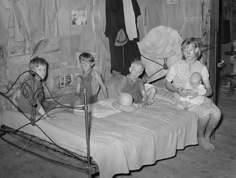25 Powerful Historical Photos That Bring Forgotten Stories Back to Life 48 Children of a farm day laborer living north of Sallisaw, Oklahoma, 1939. Inside a modest, paper-lined home used for insulation, they sit closely together on a single bed, their worn clothing and bare feet revealing the hardship faced by rural families during the Dust Bowl years. - Powerful Historical Photos