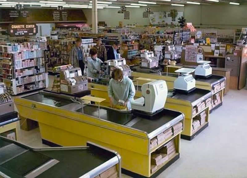 A grocery store from the late 1970s. Paper bags, giant scales, manual cash registers, and a giant cigarette display right in the middle of the store. - Rare Historical Photos In Color
