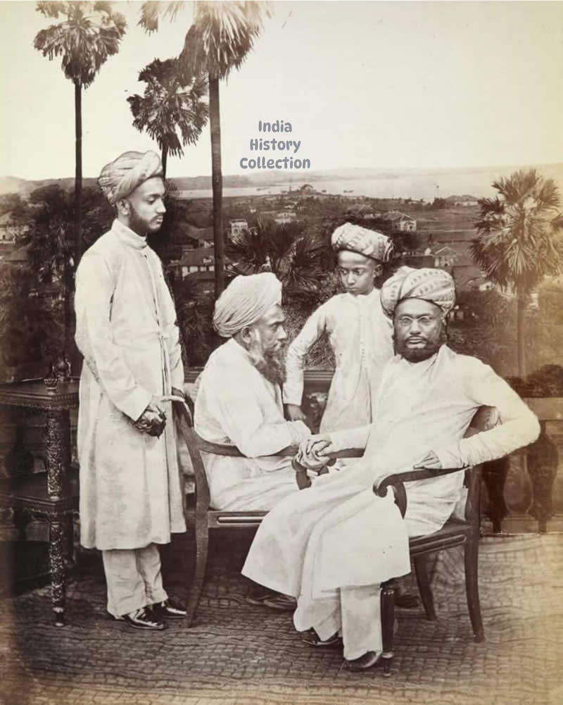 A group of Khoja men and boys, posed against a photomontaged backdrop showing an early view of Bombay — circa 1860–70s - Rare Historical Vintage Indian Photos