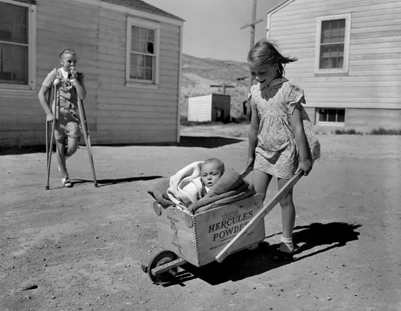 A young girl pushes her baby brother in a homemade buggy made from a Hercules Powder box in Sweetwater County, Wyoming, 1946. - Rare Historical Vintage Photos