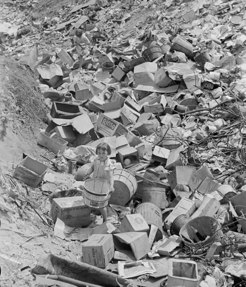 A young girl stands amid piles of discarded boxes, cans, and wooden barrels at a city dump in Ambridge, Pennsylvania, 1938. It was common for children to scavenged dumps for reusable items or materials of value - Rare Historical Vintage Photos