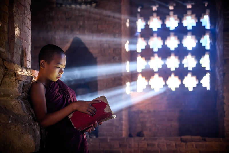 Light and peace. A novice monk, reading in silence where knowledge meets a gentle beam of light. - Travel and Cuture Photography by Erdem Kilic