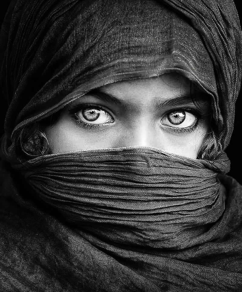 Timeless and Emotional: 30 Black and White Photos That Touch the Soul 54 Black and white close-up portrait of a person with a wrapped scarf covering most of the face, leaving only expressive eyes visible, highlighting texture, mystery, and intense gaze.