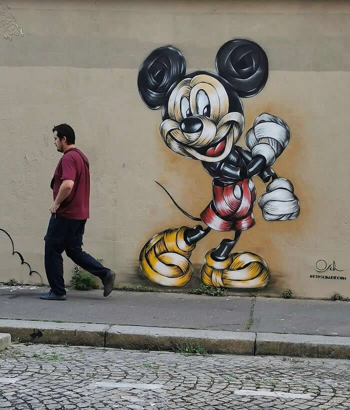 A vibrant street mural of a classic cartoon mouse character walking energetically on a wall, with a real passerby beside it, blending animation with everyday urban life. Paris, France