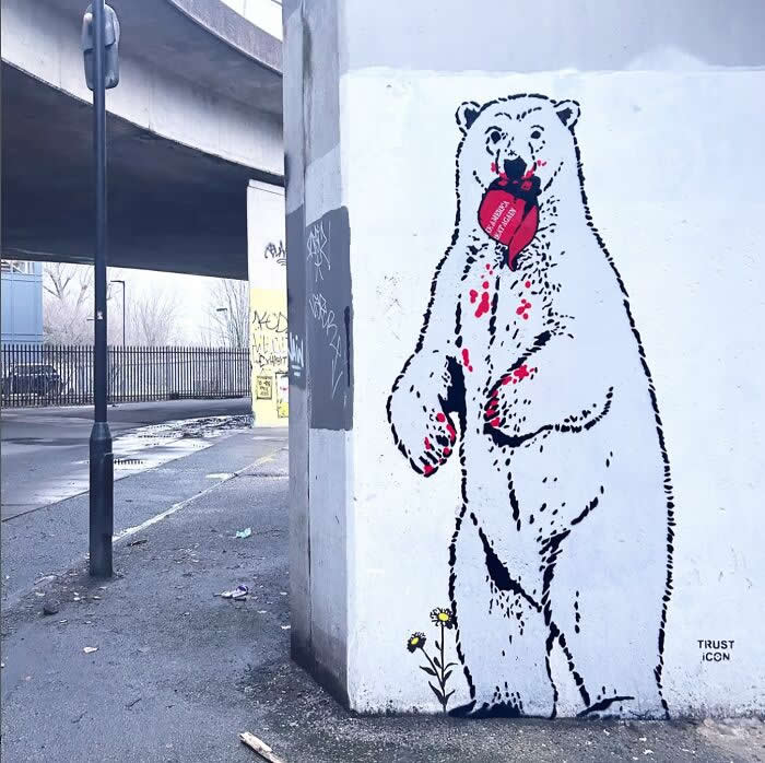 A provocative stencil-style street mural of a standing bear licking a dripping red heart, painted on a concrete wall under an overpass, symbolizing themes of trust, pain, and vulnerability. London, UK.
