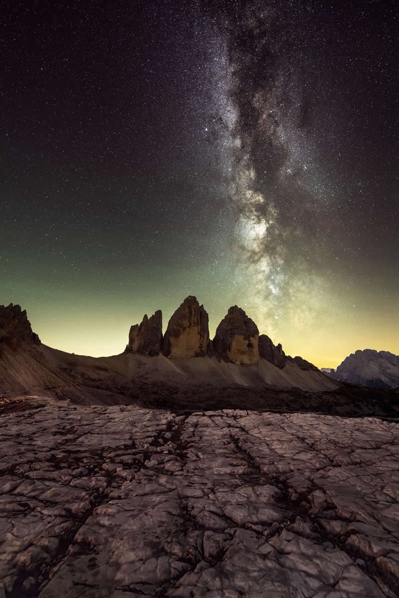 Beyond the Stars: How Mads Peter Iversen Captures the Milky Way Like No One Else 37 Milky Way galaxy rising above dramatic rocky mountain peaks with textured stone foreground under a clear star-filled night sky.