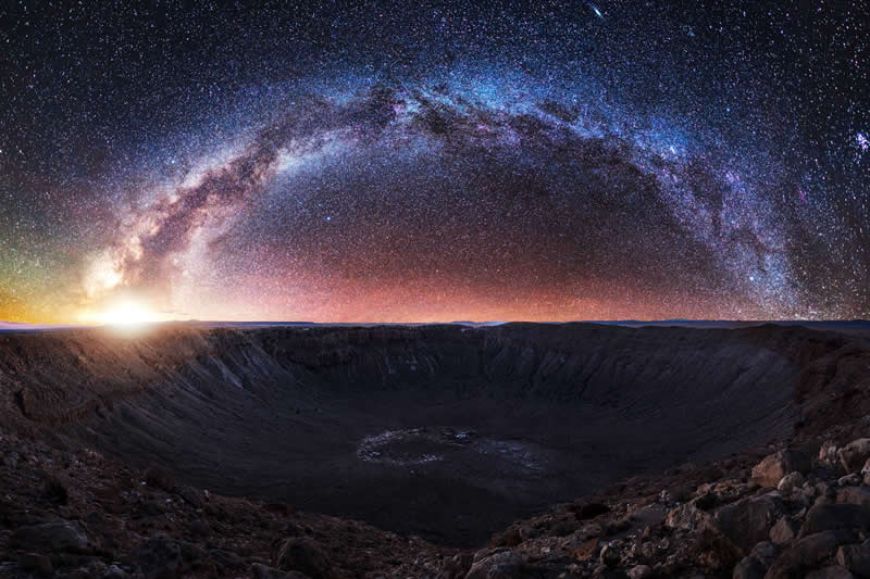 Beyond the Stars: How Mads Peter Iversen Captures the Milky Way Like No One Else 43 Milky Way galaxy arching across the night sky above a large desert crater with stars glowing over the rugged landscape.